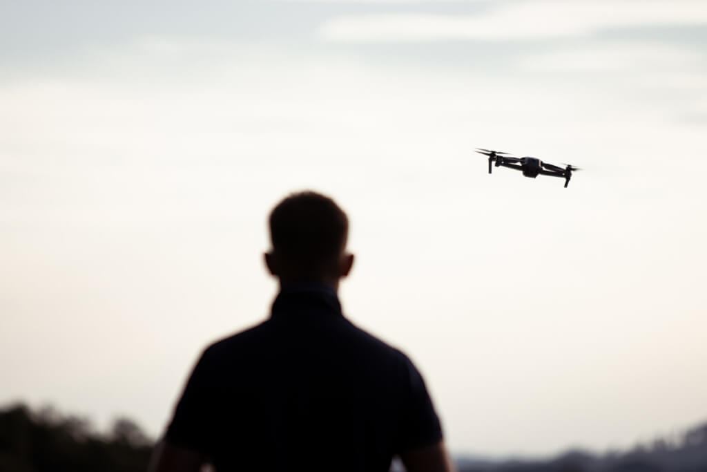 silhouette of a person flying a drone